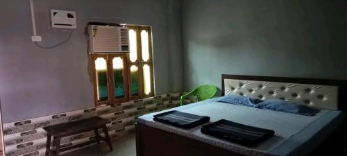 a bedroom with a bed and a window and a chair at Mahajan Guesthouse in Naimishāranya
