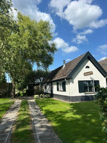 a white house with a tree and a driveway at t Olde Bakhuus in Klarenbeek