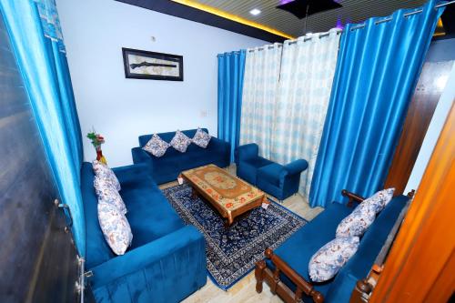 Una sala de estar con sillas azules y una mesa. en The Taj Wings Home Stay, en Agra