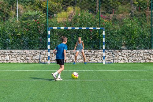 two people playing with a soccer ball on a field at MASLINICA Narcis Hotel in Rabac