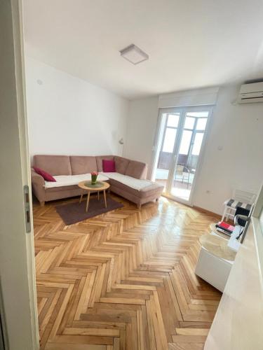 ein Wohnzimmer mit Sofa und Holzboden in der Unterkunft Apartman PARK in Trebinje