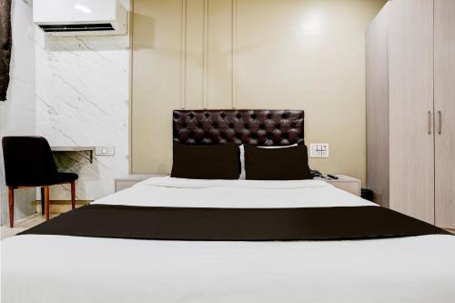 a bedroom with a large white bed with a leather headboard at Super Collection O Ulife in Mumbai