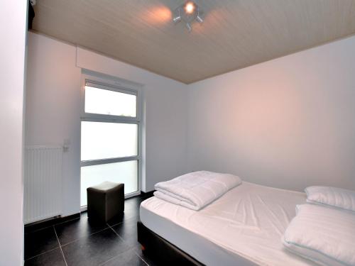 a white bedroom with a bed and a window at Luxurious Home with Sauna in Somme-Leuze