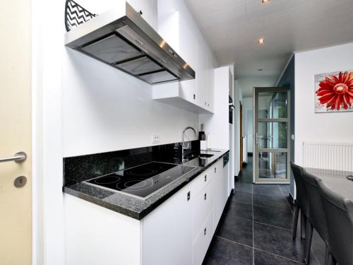 a kitchen with white cabinets and a black counter top at Luxurious Home with Sauna in Somme-Leuze