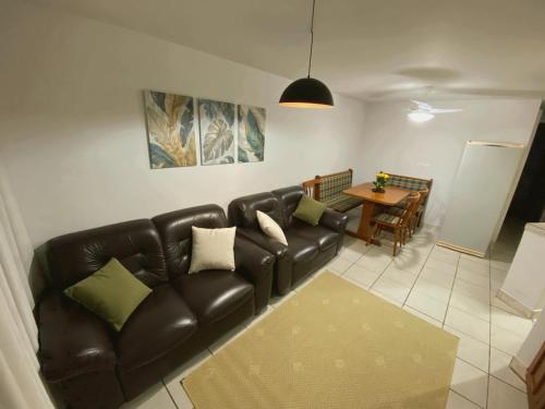a living room with a leather couch and a table at Apartamento aconchegante in Matinhos