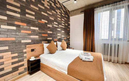 a bedroom with a bed and a brick wall at Rooms Apart Hotel by RED in Yerevan