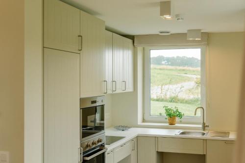 a kitchen with white cabinets and a window and a sink at La Ferme d'Auwez - Arbre de vie - Gîte 4 pers avec piscines et sauna in Ciney