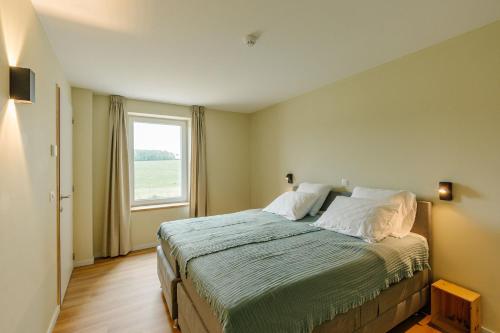 a bedroom with a large bed with a window at La Ferme d'Auwez - Arbre de vie - Gîte 4 pers avec piscines et sauna in Ciney