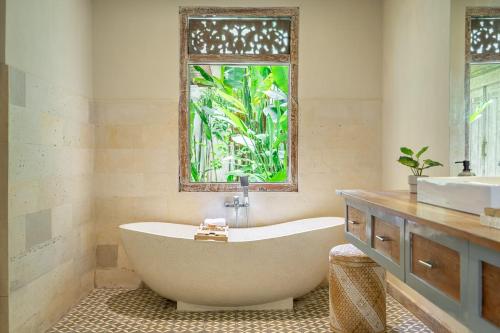 una bañera en un baño con ventana en LePalms villa, 2min Beach, 10min Atlas,Finns Club, en Canggu