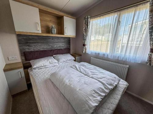 a bedroom with a white bed in a room with a window at Modern Caravan With Decking At Valley Farm, Essex Ref 46112V in Great Clacton