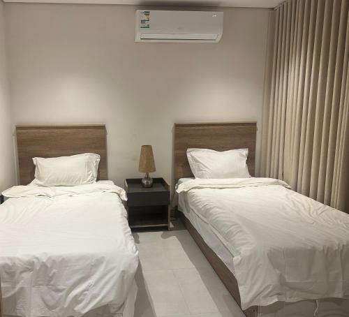 a bedroom with two beds and a table with a lamp at أجنحة رافينا هاوس - Ravina Suites in Riyadh