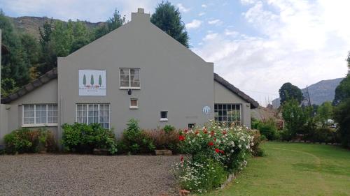 a white house with flowers in front of it at Bergvliet Cottages - Salvado and Esparanza in Clarens