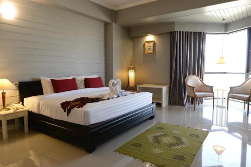 a bedroom with a bed and a table and chairs at Napalai Hotel in Udon Thani