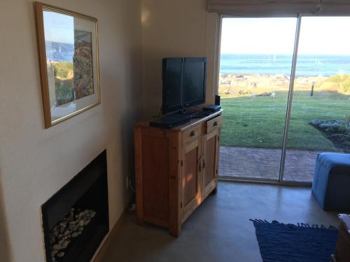 赫曼努斯Oceans Edge - Hermanus Beach Club的客厅设有带壁炉的梳妆台,配有电视