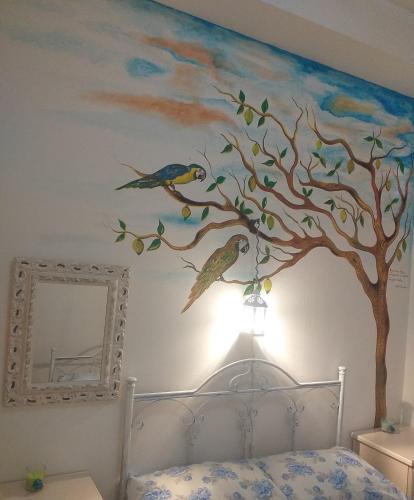 a bedroom with a tree and two birds on the wall at Casa Lasca in San Marzano di San Giuseppe