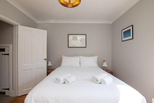 Un dormitorio con una cama blanca con dos toallas encima. en Central 2 BD Townhouse, en Stratford-upon-Avon