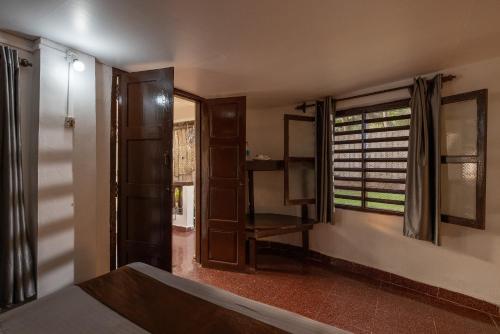 a room with a bed and a window and a door at Forget Me Not Resort in Agonda