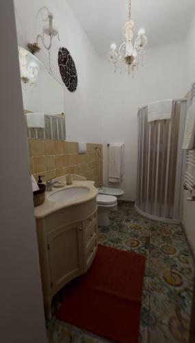 a bathroom with a sink and a toilet and a chandelier at Dimora Donna Carmela in Capaci