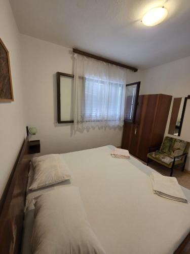 a large white bed in a room with a window at Apartman Antica in Komiža