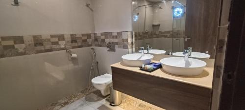 a bathroom with two sinks and a toilet and a shower at Montecarlo Hotel in Mahabalipuram