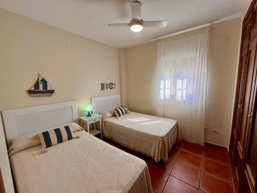 ein kleines Zimmer mit zwei Betten und einem Fenster in der Unterkunft Casa Verdemar Golf Islantilla in Islantilla