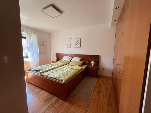 a bedroom with a bed with a wooden headboard at Ferienwohnung Bliesgau in Blieskastel