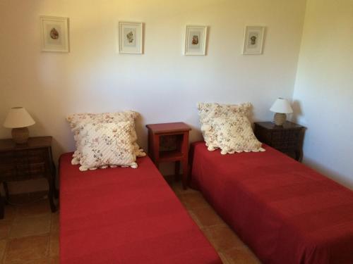 - 2 lits dans une chambre avec des draps et des oreillers rouges dans l'établissement Le Putt-Tee Bastidon, à Nans-les-Pins