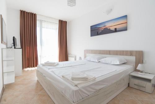 a white bedroom with a large bed and a window at Oasis Resort & Spa Cozy Apartments in Lozenets