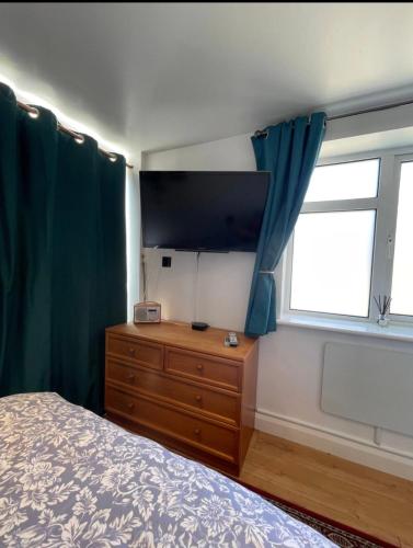 a bedroom with a bed and a dresser with a television at Shangri-La in Chesham