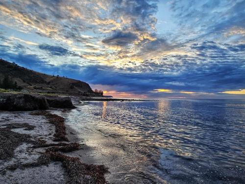a beach with a cloudy sky and the water at Lady Bay Beach House - seconds from the sand in Normanville