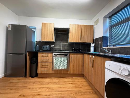 a kitchen with wooden cabinets and a stainless steel refrigerator at Comfy 3 Bedroom House Near CovArena & TrainStation in Exhall
