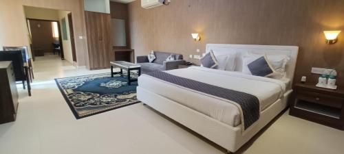 a bedroom with a large white bed and a couch at Montecarlo Hotel in Mahabalipuram