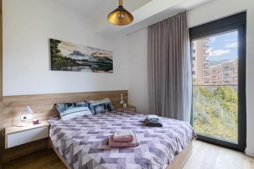 Un dormitorio con una cama y una ventana grande. en Aura Zafiro, en Budva