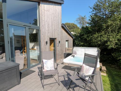 a patio with a bed and two chairs and a table at Cornerstones Brython in Tenby