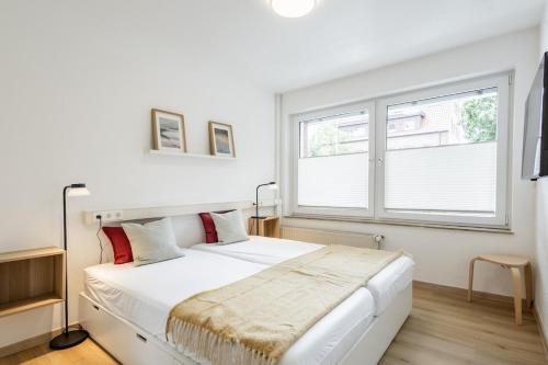 a white bedroom with a large bed and a window at Ems-Suite 01 I City I WiFi I 4 Personen I Klimaanlage in Warendorf