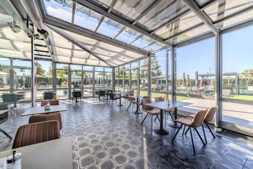 a restaurant with tables and chairs and large windows at Hotel Aura Design & Garden Pool in Prague