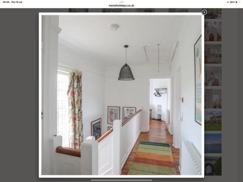 a hallway with white walls and a staircase with a colorful rug at Coastal Family Escape with Castle Views in Deganwy