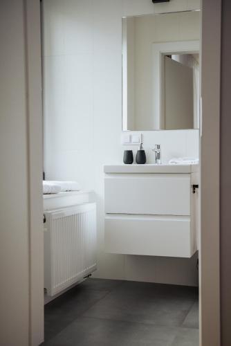 a white bathroom with a sink and a mirror at Apartamenty Janasa 13 in Chorzów