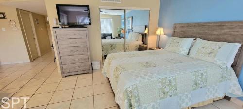 a bedroom with a bed and a dresser with a television at Gulfview I #205 in South Padre Island