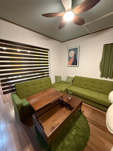 a living room with a green couch and a ceiling fan at 柳生のおやど in Toyohashi