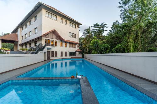 a swimming pool in front of a building at Still Waters Alaya Stays by ELIVAAS in Varkala
