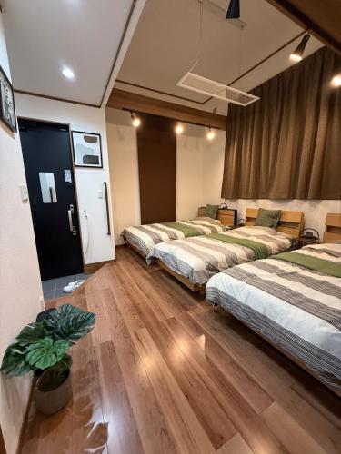 three beds in a room with wooden floors at 柳生のおやど in Toyohashi