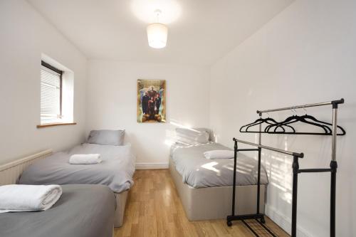 two twin beds in a room with white walls at Southernwood House Long Stays Free Parking WiFi in Swindon