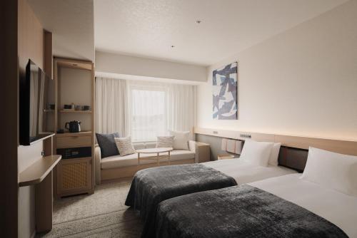 a hotel room with two beds and a couch at THE NEST NAHA in Naha