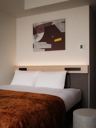 a bedroom with a bed and a painting on the wall at THE NEST NAHA in Naha