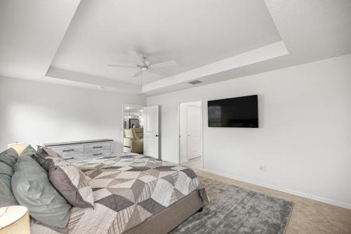 Un dormitorio con una cama y un televisor de pantalla plana. en Spacious Lake View 3BR in The Villages With Golf Cart & Patio, en Sumterville