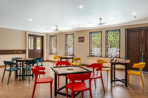 a restaurant with colorful chairs and tables and windows at Still Waters Alaya Stays by ELIVAAS in Varkala