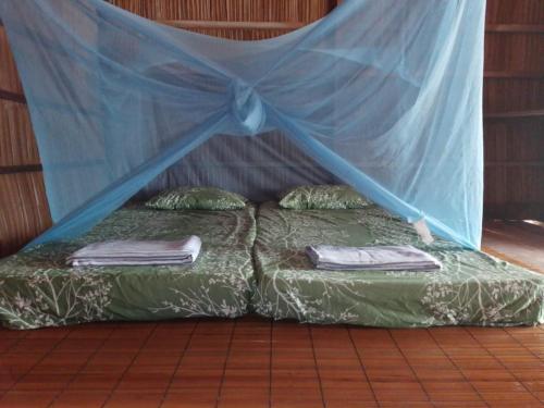 MantaakにあるHelda Homestayの蚊帳付きの客室内のベッド2台
