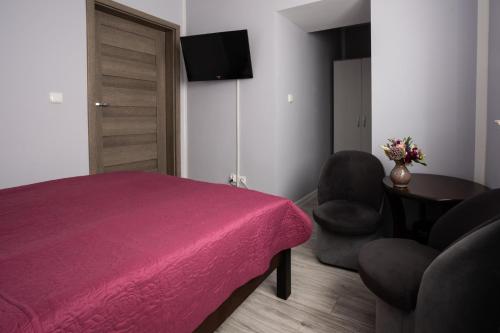 a bedroom with a bed and two chairs and a television at Pablo in Niechorze