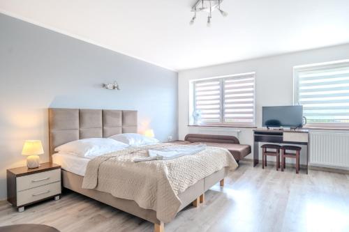 a bedroom with a bed and a desk with a tv at Pablo in Niechorze